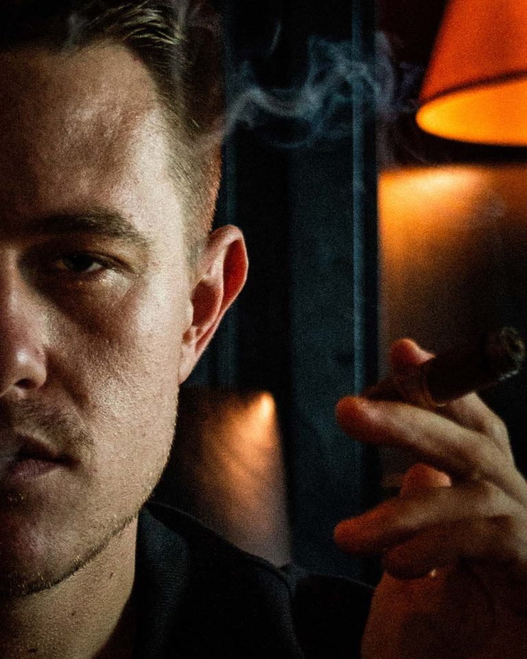 Cinematic portrait of a man holding a cigar, photographed by Cyrus Media in Ottawa, Ontario.