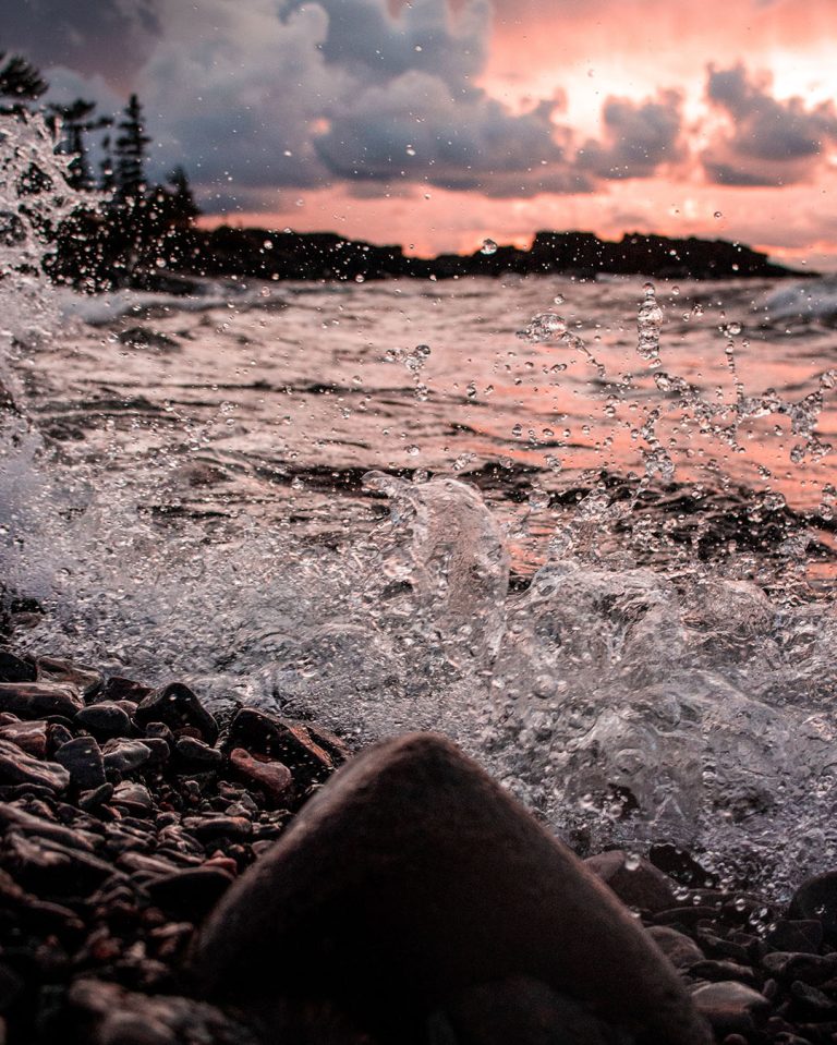 Scenic view of Lake Superior on the Canadian side with rocky shoreline and red sunset.